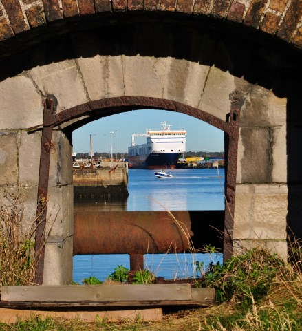 Window into a view of the past and the now... a glimpse through old stone wall at a ferry and speed boat in Dublin's harbour area...